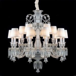 A magnificent 12-arm crystal chandelier with white fabric lampshades and cascading crystal prisms against a black background.