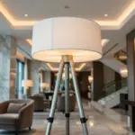 A technical infographic of a luxury tripod floor lamp featuring the RST logo on a modern wall. It highlights high-tensile alloy construction, CNC-machined joints, and a hand-rolled fabric shade, with icons for Zigbee and DALI smart integration.