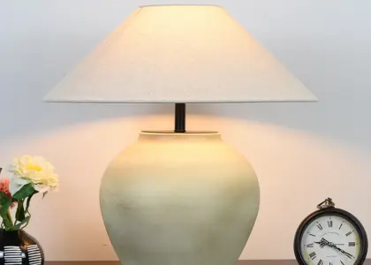 Large handcrafted ceramic vase table lamp with a beige fabric shade in a luxury hotel setting.
