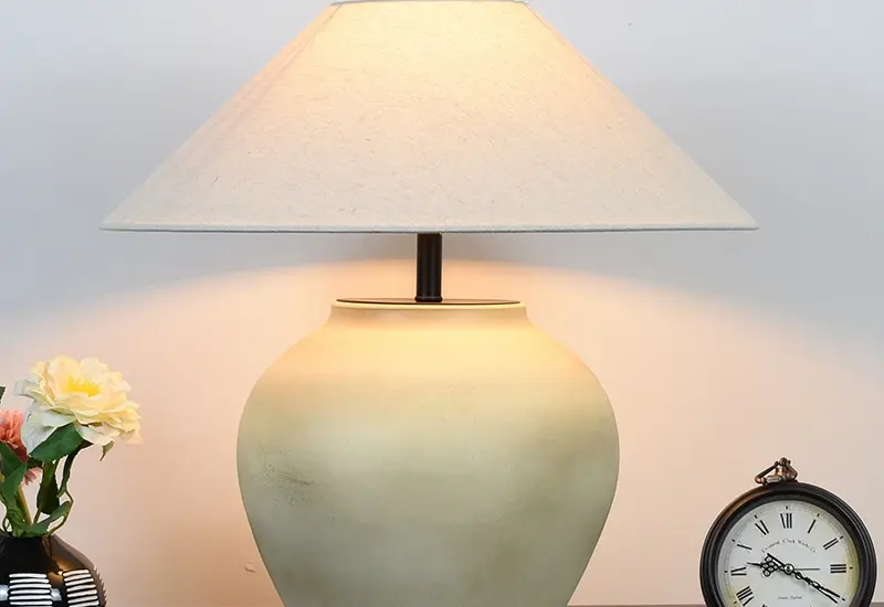 Large handcrafted ceramic vase table lamp with a beige fabric shade in a luxury hotel setting.