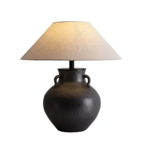 Matte black textured ceramic table lamp with amphora handles and tan fabric shade for luxury hotel decor.