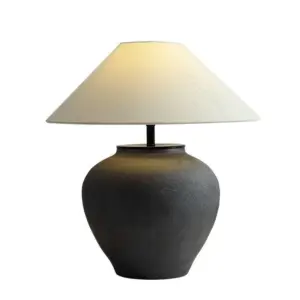 Industrial charcoal matte ceramic table lamp with wide urn base and conical linen shade for luxury hospitality.