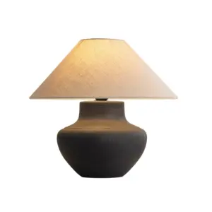Dark basalt rock texture ceramic table lamp with wide squat base and conical linen shade for luxury hotel projects.