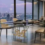RST Luxury Glass Mahjong Table featuring a minimalist tempered glass design with a black playing surface in a high-end skyscraper penthouse at twilight.