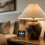 Earth tone rustic ceramic table lamp with tan fabric shade for luxury hotel bedside lighting.