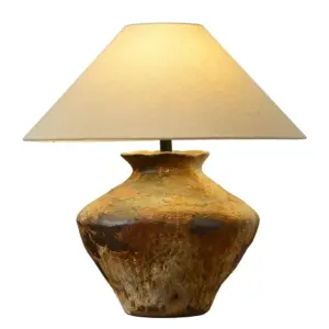 Earth tone rustic ceramic table lamp with tan fabric shade for luxury hotel bedside lighting.