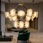 RST brand modern handcrafted brass and natural alabaster chandelier installed in a luxury hotel lobby with a gold RST logo on the marble wall.