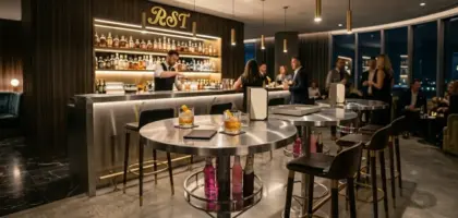 Custom F-1059 brushed stainless steel commercial high bar tables with built-in bottle storage in a luxury high-traffic sky lounge interior.