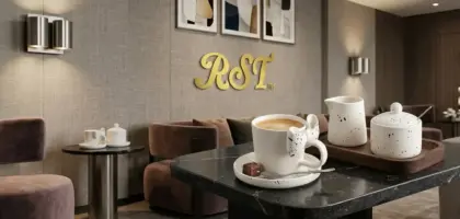 Premium RST ceramic coffee cup with a creative bow ribbon handle on a marble table inside a modern luxury hotel lounge, elevating hospitality interior design.